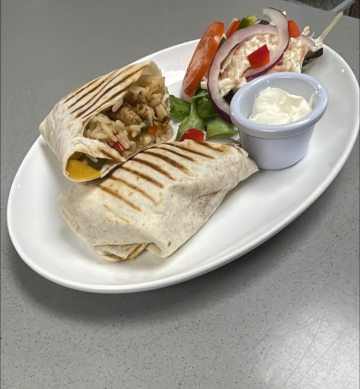 Grilled chicken burrito with salad and sour cream